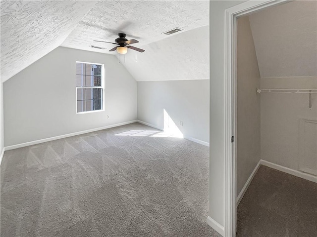 bonus room with vaulted ceiling, carpet, visible vents, and a textured ceiling