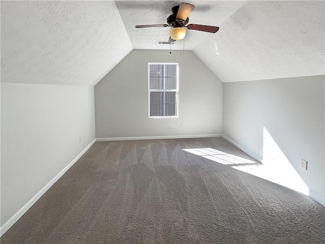 additional living space featuring vaulted ceiling, visible vents, carpet floors, and a textured ceiling