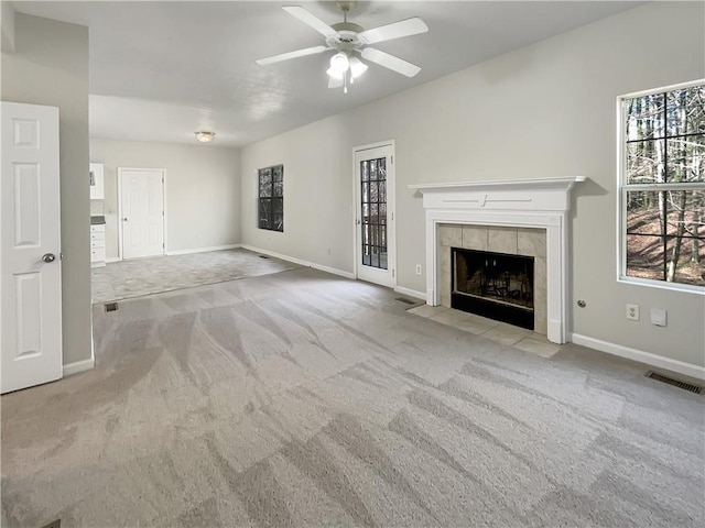 unfurnished living room featuring a tiled fireplace, carpet flooring, baseboards, and visible vents