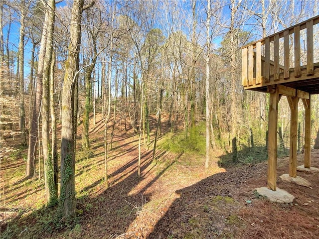 view of yard featuring a wooden deck and a wooded view