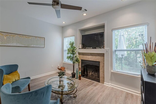 sitting room featuring a tiled fireplace, hardwood / wood-style floors, ceiling fan, and plenty of natural light