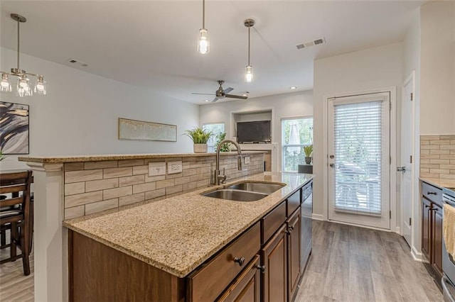 kitchen featuring light hardwood / wood-style floors, hanging light fixtures, sink, and backsplash