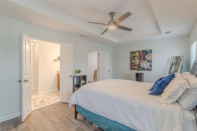 bedroom featuring light hardwood / wood-style floors, ceiling fan, and a tray ceiling