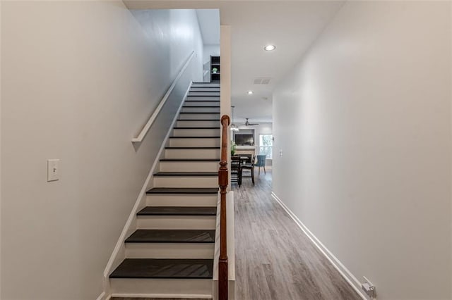 stairway featuring wood-type flooring and ceiling fan