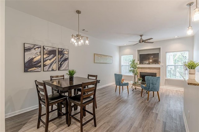 dining space with hardwood / wood-style flooring and ceiling fan with notable chandelier