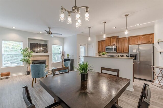 dining space with ceiling fan with notable chandelier and light hardwood / wood-style floors