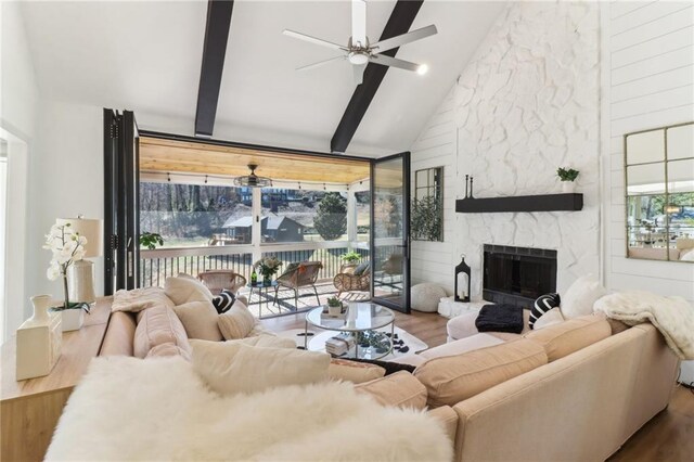 living area with a wealth of natural light, a stone fireplace, and wood finished floors