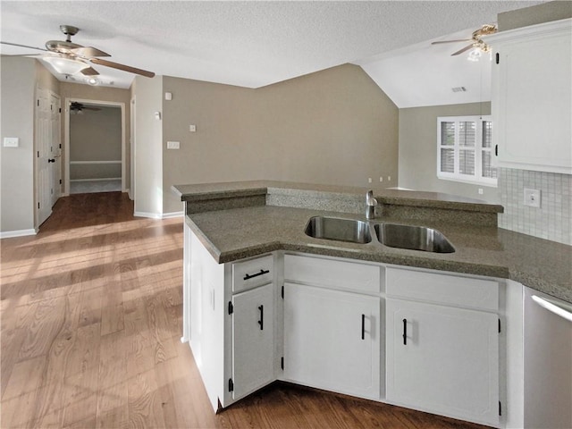 kitchen featuring light wood-type flooring, a sink, backsplash, white cabinets, and vaulted ceiling