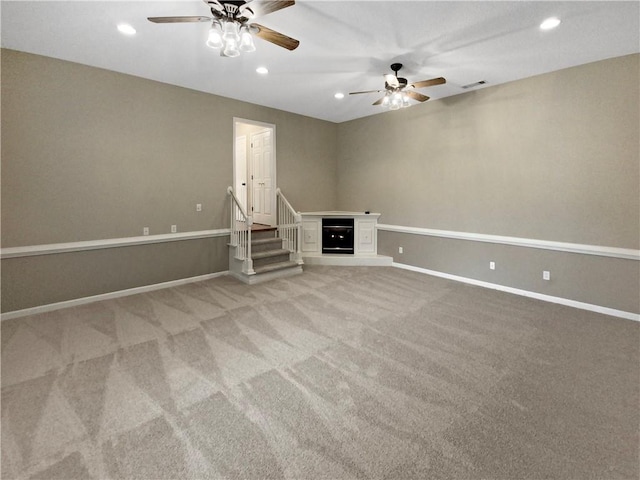 spare room featuring visible vents, baseboards, recessed lighting, light carpet, and a glass covered fireplace