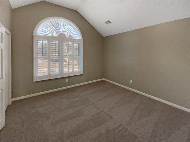 empty room with lofted ceiling, carpet flooring, baseboards, and visible vents