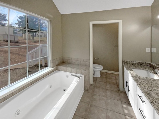 bathroom with tile patterned flooring, a jetted tub, toilet, vaulted ceiling, and vanity