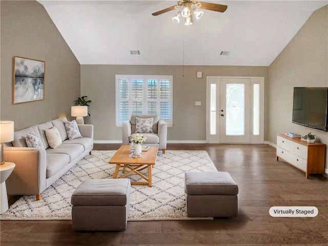 living area featuring baseboards, a healthy amount of sunlight, wood finished floors, and vaulted ceiling