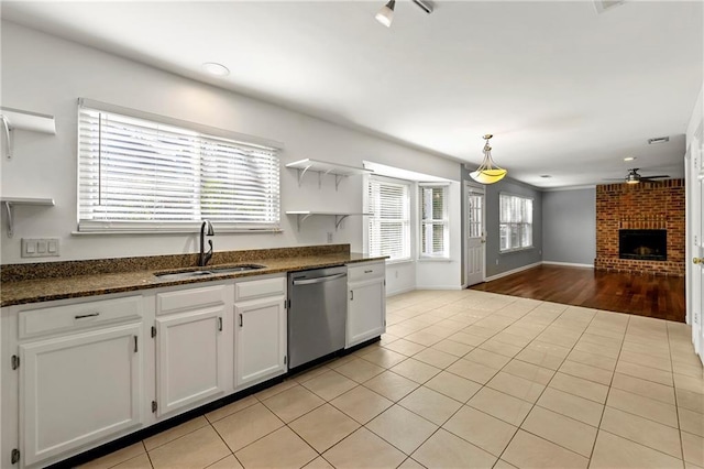 kitchen featuring dishwasher, open floor plan, a brick fireplace, open shelves, and a sink