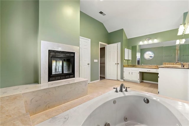 full bath featuring visible vents, vanity, vaulted ceiling, a high end fireplace, and a jetted tub