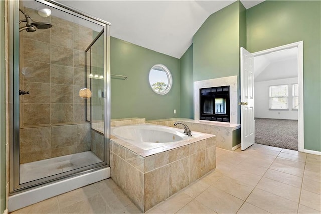 bathroom featuring lofted ceiling, a shower stall, a bath, and tile patterned floors