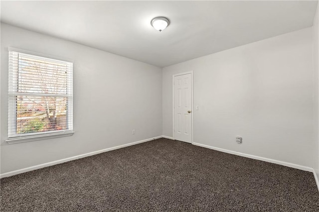 empty room with dark colored carpet and baseboards