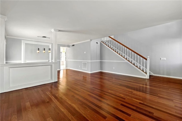 unfurnished living room featuring visible vents, baseboards, stairway, wood finished floors, and crown molding