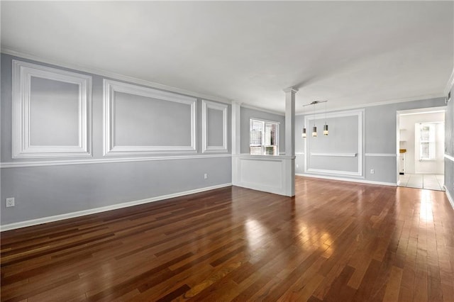 unfurnished living room featuring baseboards, crown molding, hardwood / wood-style floors, and decorative columns