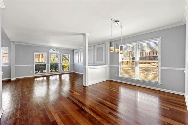 unfurnished living room with baseboards, a healthy amount of sunlight, dark wood-style flooring, and ornate columns