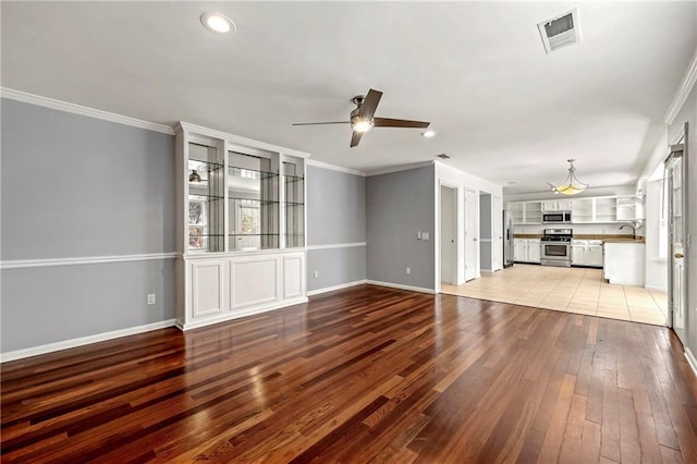 unfurnished living room featuring baseboards, light wood-style flooring, visible vents, and crown molding