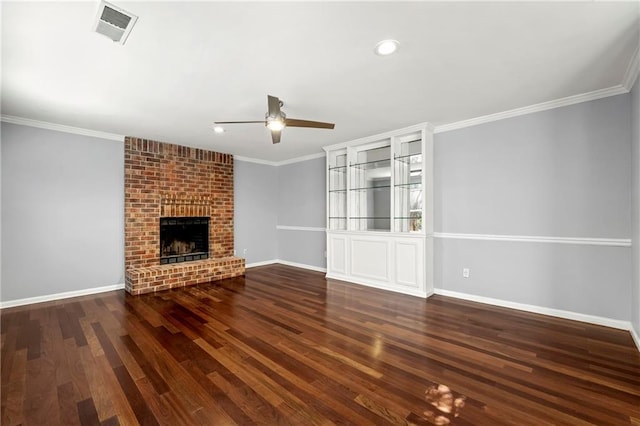 unfurnished living room featuring ornamental molding, a brick fireplace, visible vents, and wood finished floors