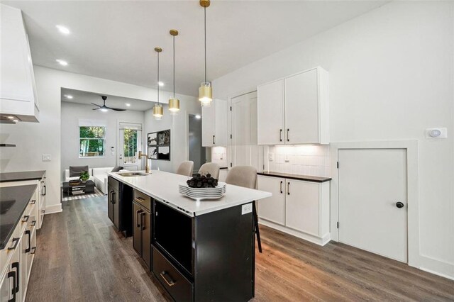 kitchen featuring sink, white cabinetry, hanging light fixtures, an island with sink, and dark hardwood / wood-style flooring