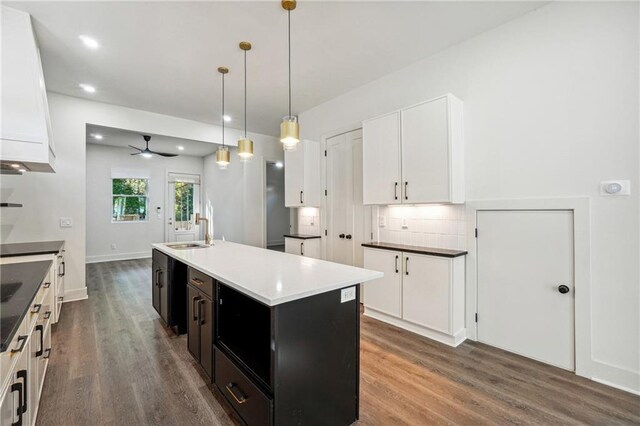 kitchen with white cabinetry, an island with sink, stainless steel built in fridge, and premium range hood