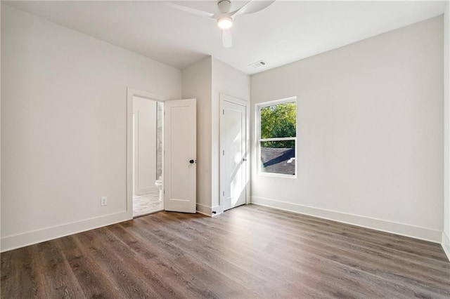 empty room with ceiling fan and dark hardwood / wood-style flooring