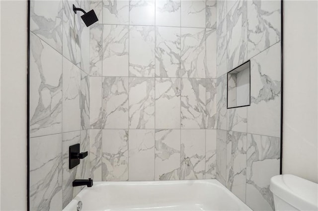 bathroom featuring tiled shower / bath combo and toilet