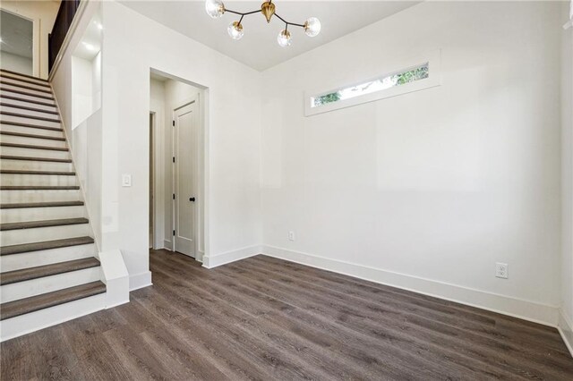 empty room featuring an inviting chandelier and dark hardwood / wood-style floors