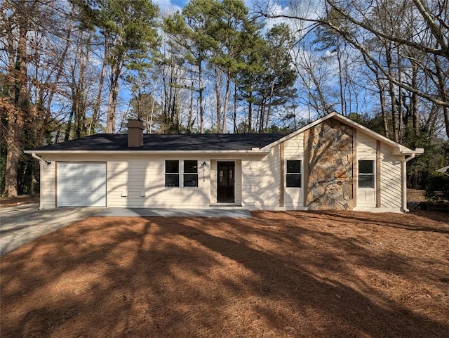 view of front of property with stone siding, concrete driveway, a chimney, and a garage