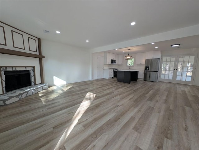 unfurnished living room featuring recessed lighting, french doors, light wood-style flooring, and a premium fireplace