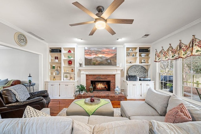 living area featuring visible vents, ceiling fan, ornamental molding, dark wood-style flooring, and a brick fireplace