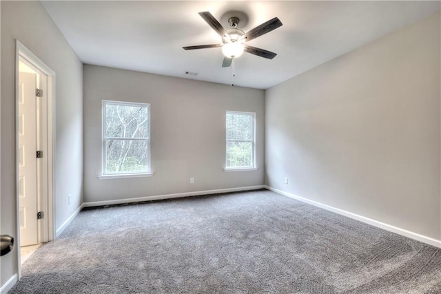 carpeted empty room with ceiling fan and a wealth of natural light