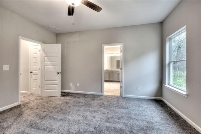 unfurnished bedroom with multiple windows, ceiling fan, carpet, and ensuite bath