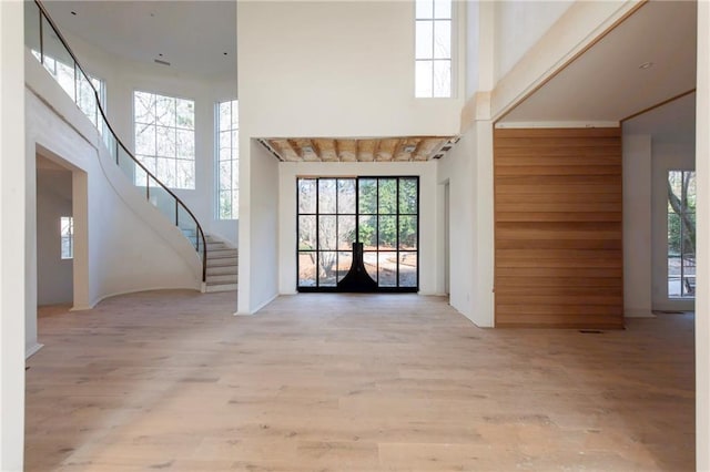 foyer entrance with french doors, a towering ceiling, and light hardwood / wood-style floors