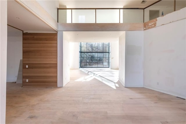 hallway with a high ceiling and light hardwood / wood-style floors