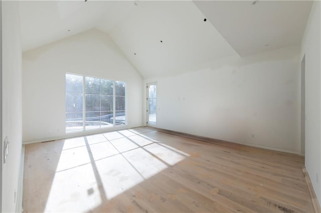 spare room featuring high vaulted ceiling and light hardwood / wood-style flooring