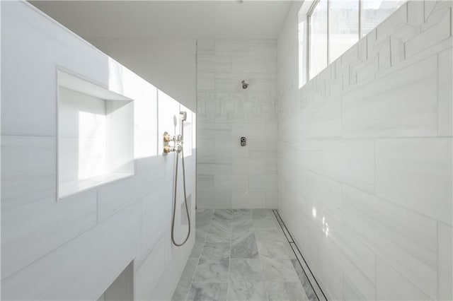 bathroom featuring a tile shower and a wealth of natural light