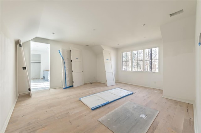 unfurnished room with vaulted ceiling and light wood-type flooring