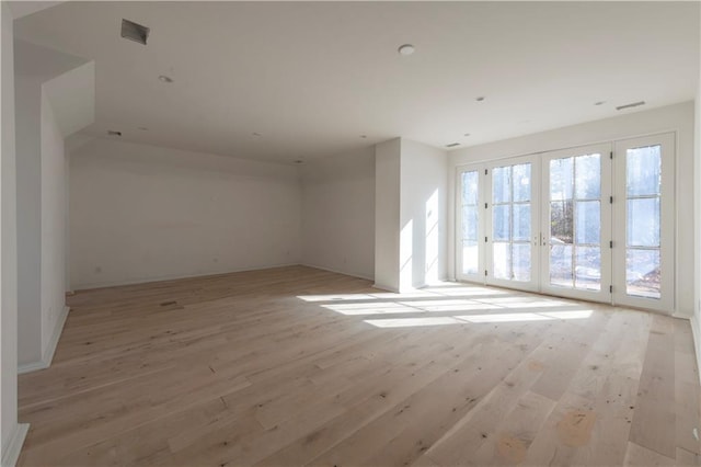 empty room with light hardwood / wood-style floors and french doors