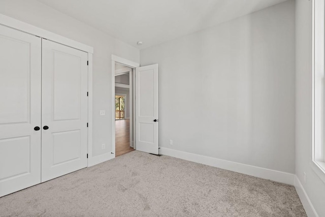 unfurnished bedroom featuring light colored carpet and a closet