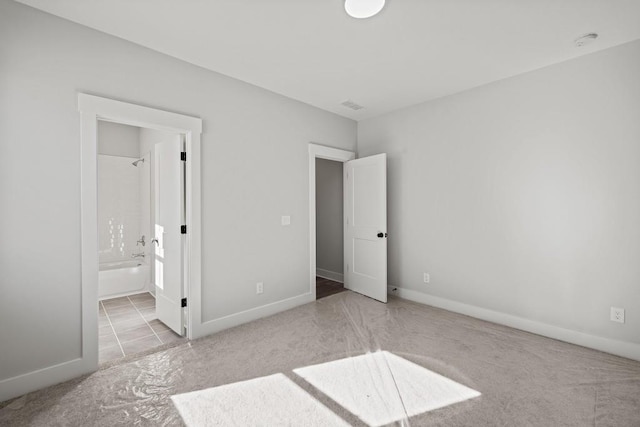 unfurnished bedroom featuring ensuite bath and light colored carpet