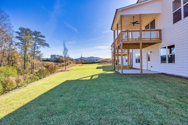 view of yard with a deck with mountain view, ceiling fan, and a patio area