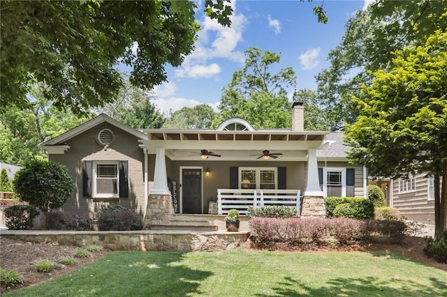 back of house with ceiling fan, covered porch, and a lawn