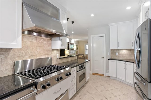 kitchen with light tile patterned floors, appliances with stainless steel finishes, white cabinetry, hanging light fixtures, and extractor fan