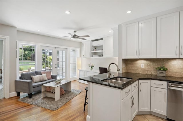 kitchen featuring sink, a breakfast bar area, white cabinets, stainless steel dishwasher, and kitchen peninsula