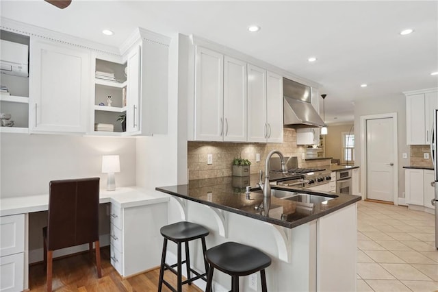 kitchen with sink, a breakfast bar area, built in desk, white cabinets, and kitchen peninsula