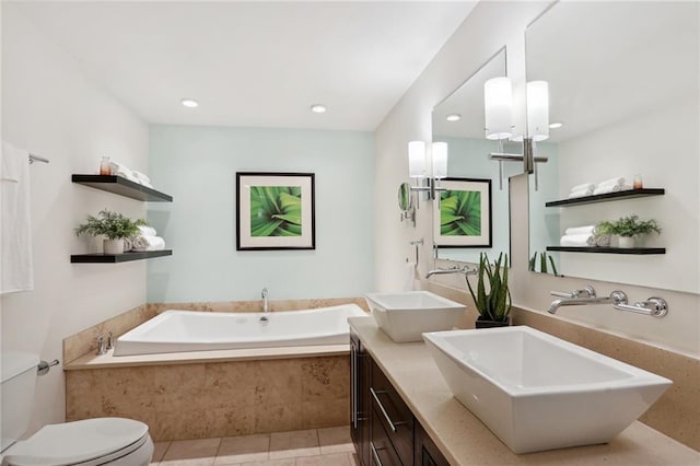 bathroom with a relaxing tiled tub, vanity, toilet, and tile patterned flooring