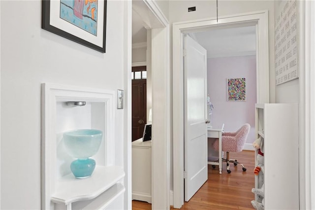 hallway featuring crown molding and light hardwood / wood-style flooring